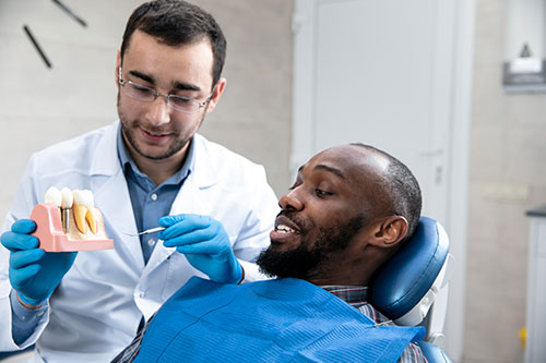 dentist showing a patient a tooth model