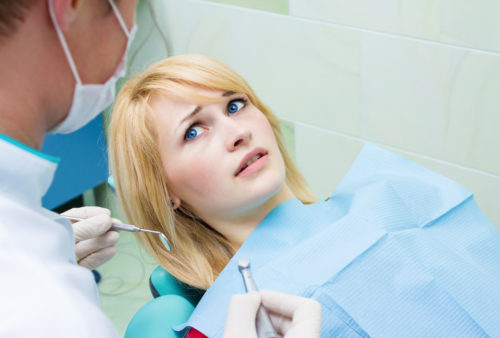 anxious patient looking up at doctor from dental chair